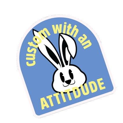 Blue sticker with smiling cartoon bunny illustration and “Custom with an Attitude” slogan, playful custom graphic design