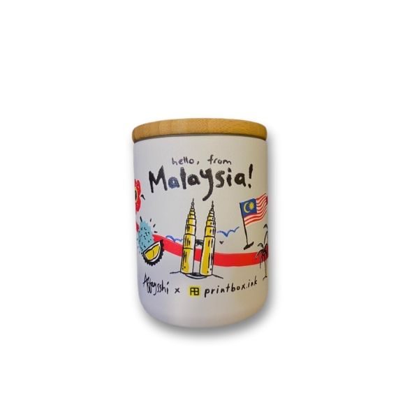 White ceramic jar with a bamboo lid, featuring a colorful illustration of the Petronas Twin Towers, a Malaysian flag, and tropical elements, along with the text 'Hello, from Malaysia!' and 'Agnysashi x printbox.ink'.