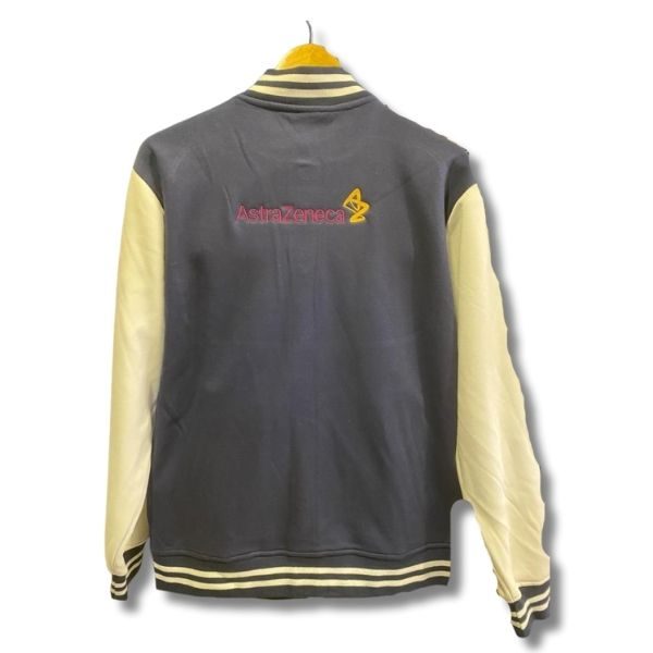 Back view of a varsity jacket with yellow sleeves and striped collar, featuring the 'AstraZeneca' logo and emblem in pink and yellow on the upper back.