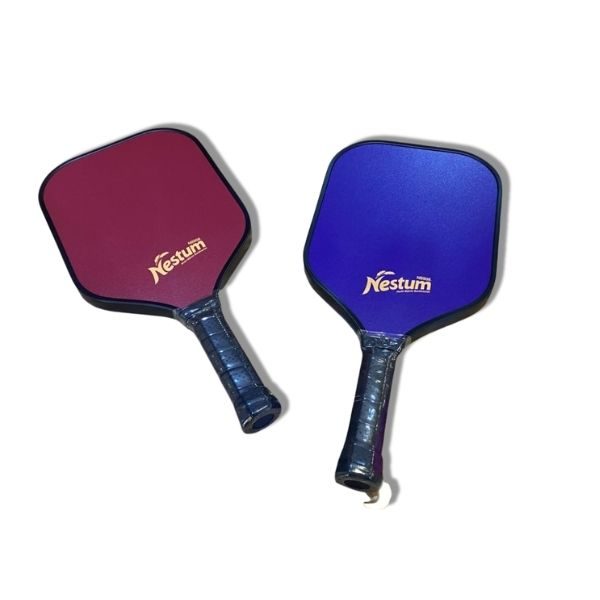 Two paddle rackets with 'Nestum' branding: one maroon and one blue, both with a black border and a transparent handle